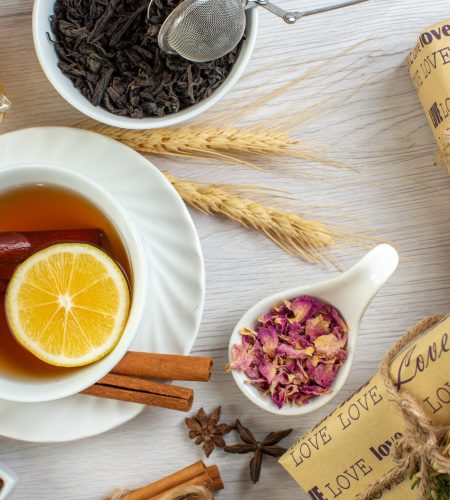 Tasse de thé avec morceau de citron. Entouré d'épi de blé, cannelle, fleurs et feuille de thé